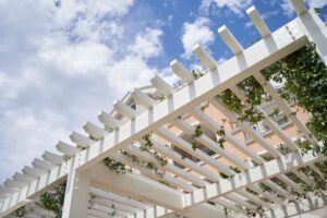 Close-up view of a white pergola with ivy growing along the top