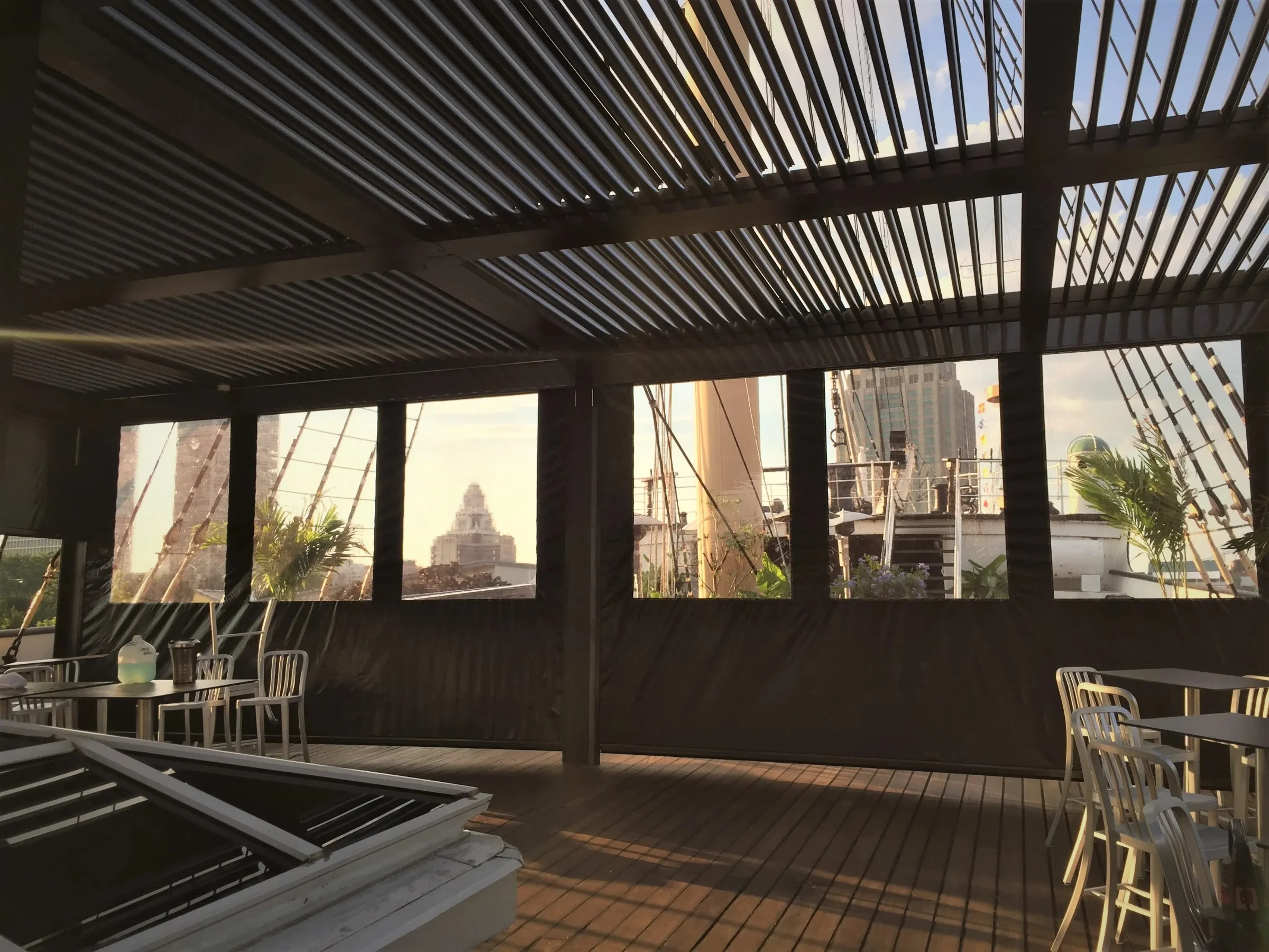 Interior view through a dark motorized pergola louvered roof over a Florida patio lounge