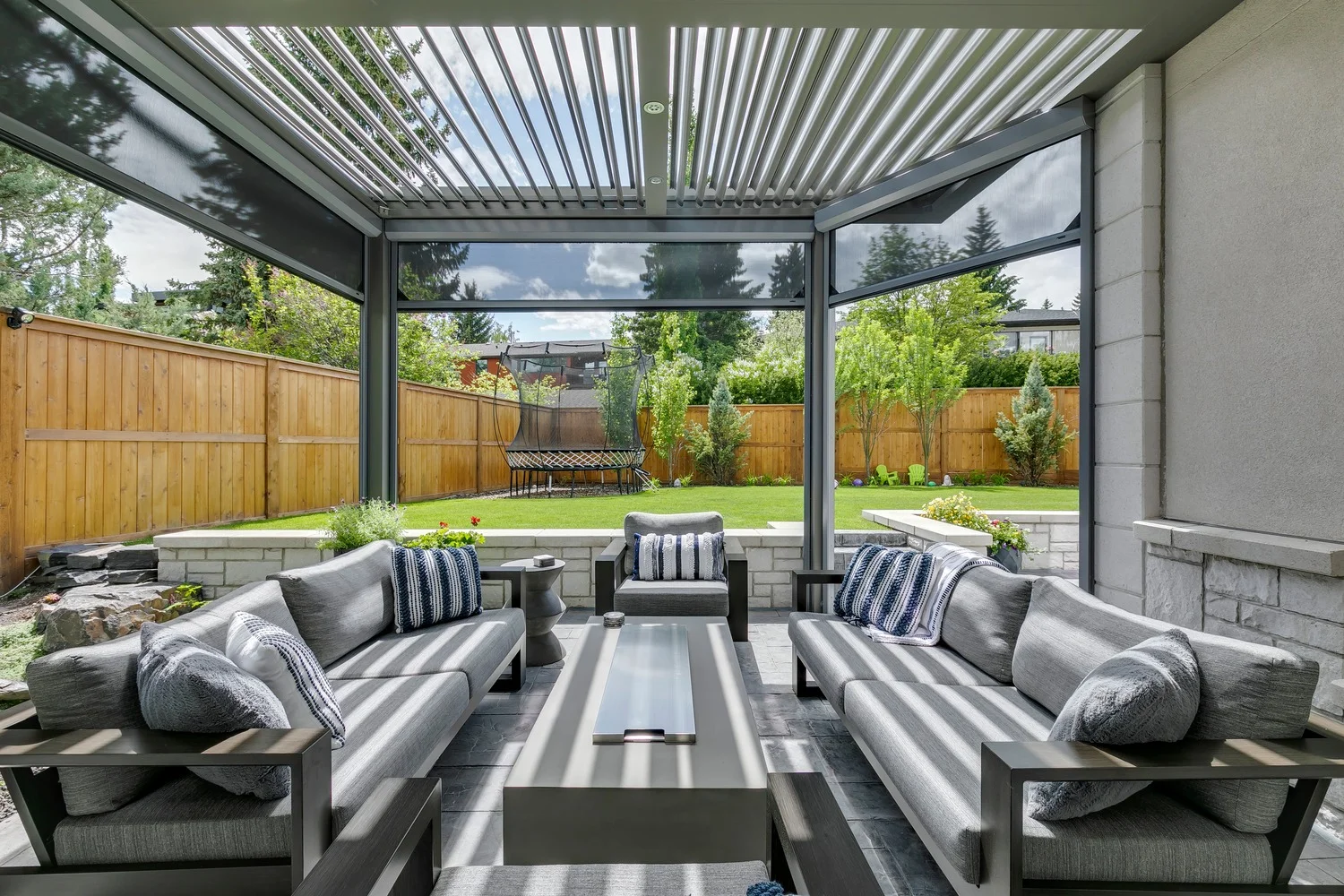 Dark StruXure louvered pergola with motorized screens and outdoor TV creating a screened entertainment space
