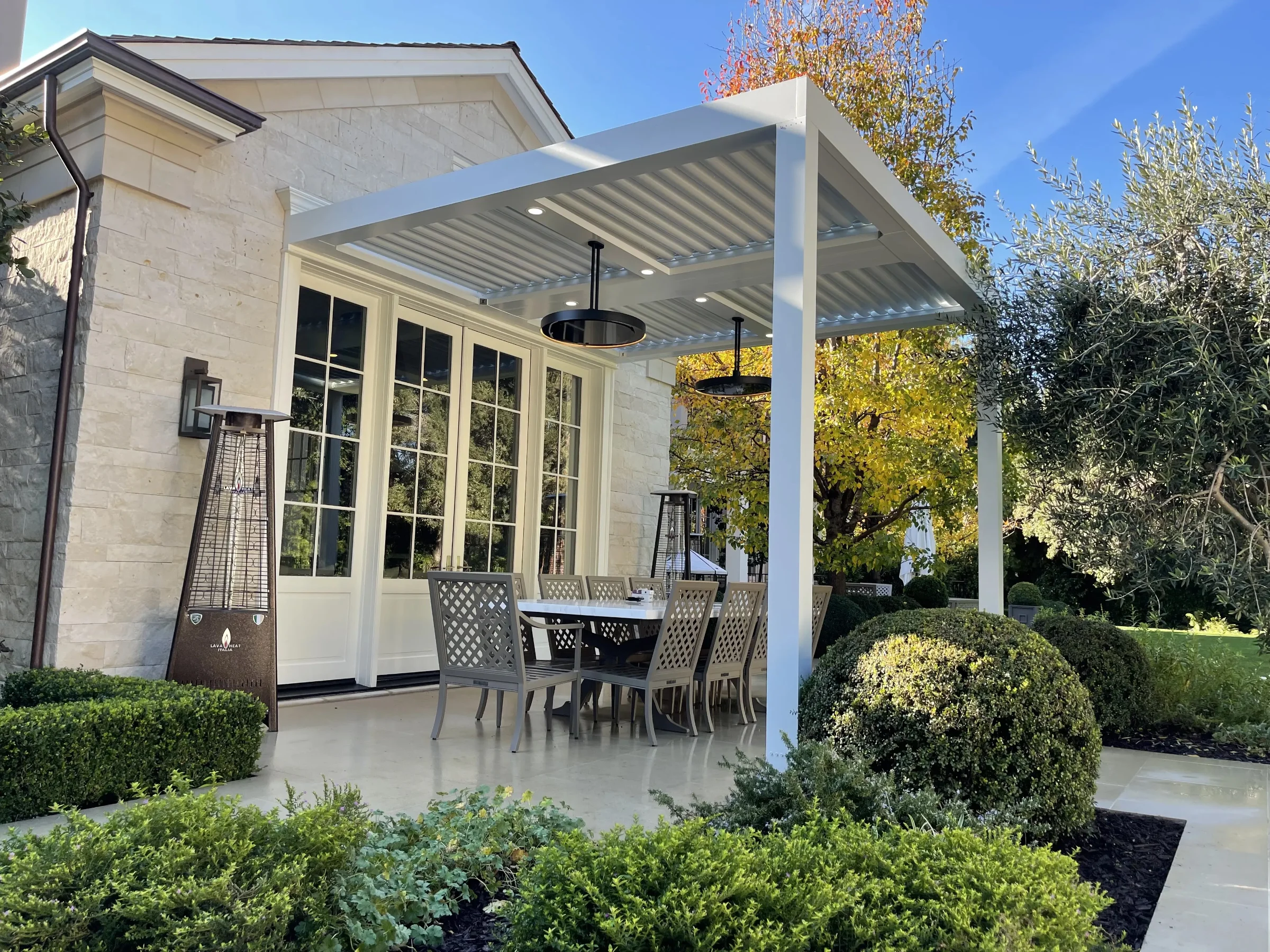 White columns supporting a covered outdoor room beside a Florida garden