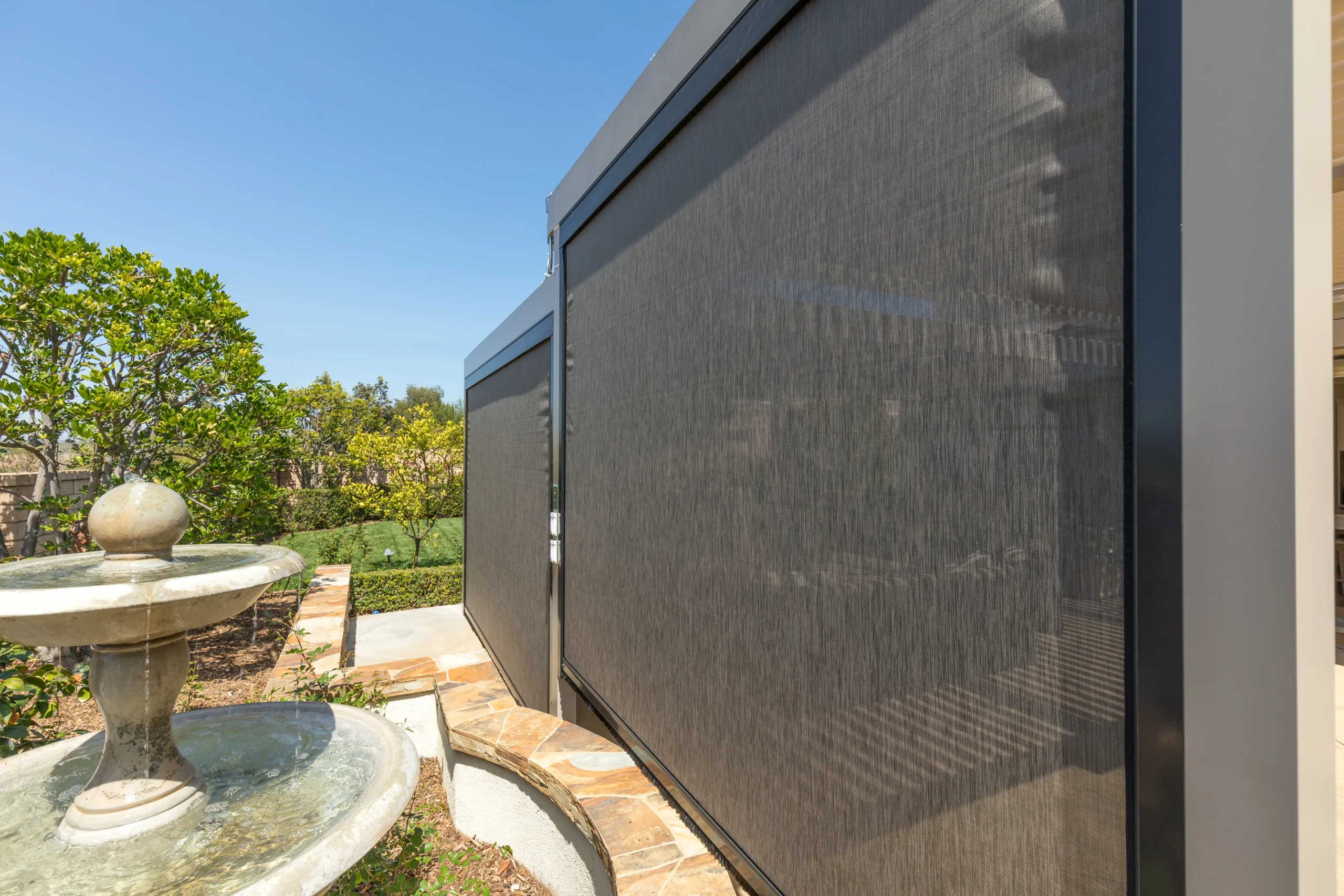 Dark motorized privacy screen fully deployed on a South Florida patio pergola