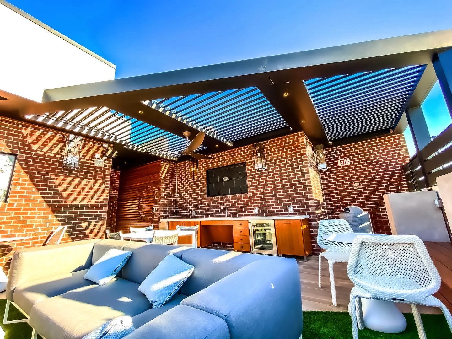 Louvered aluminum pergola with integrated lighting on an elevated outdoor terrace