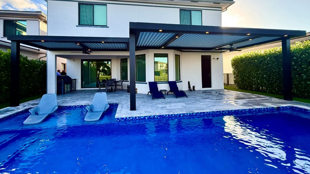 Dark louvered pergola over a pool deck with loungers at a South Florida home
