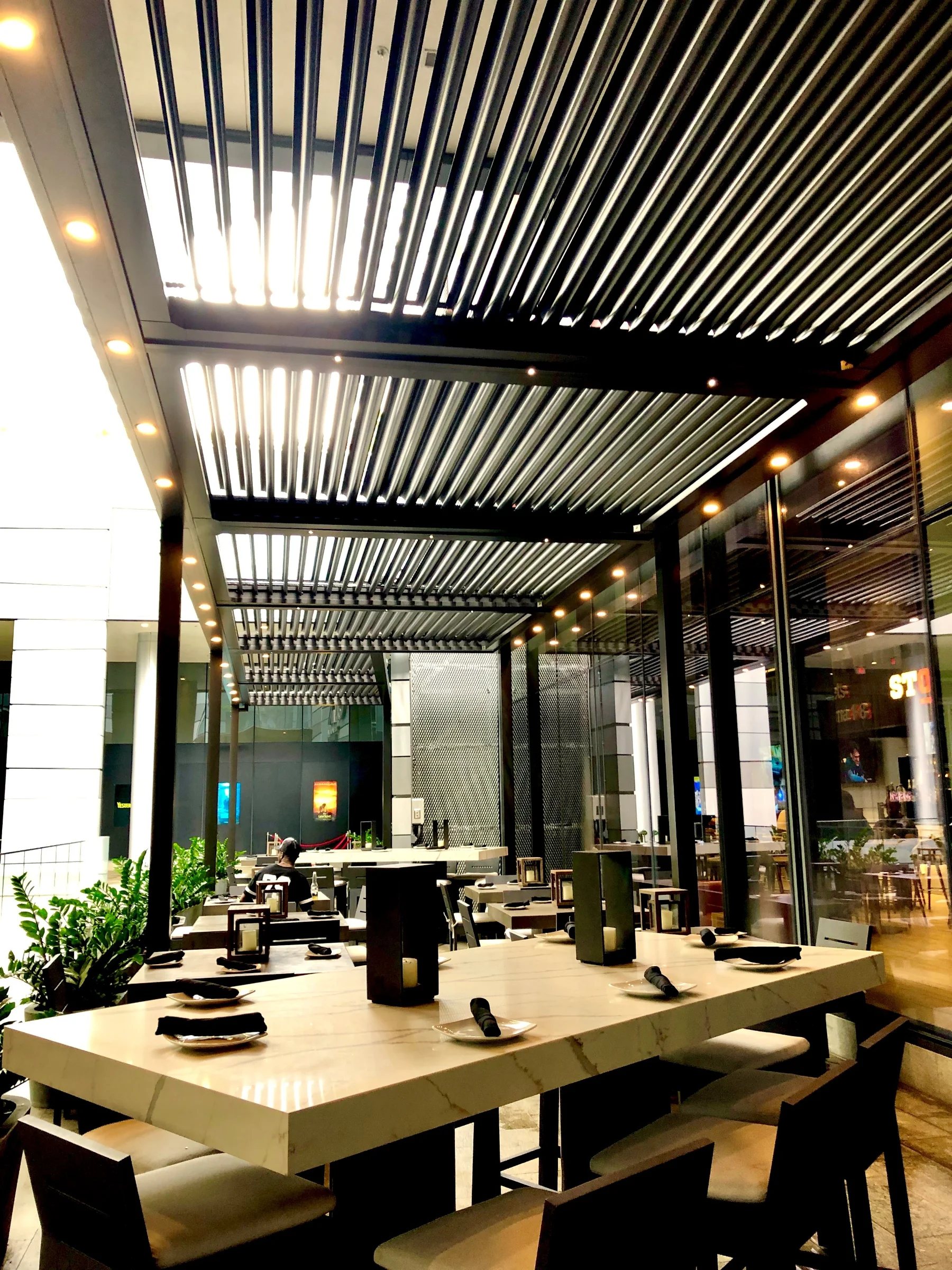 Looking up through open louvers of a motorized pergola showing the rotating aluminum louver system
