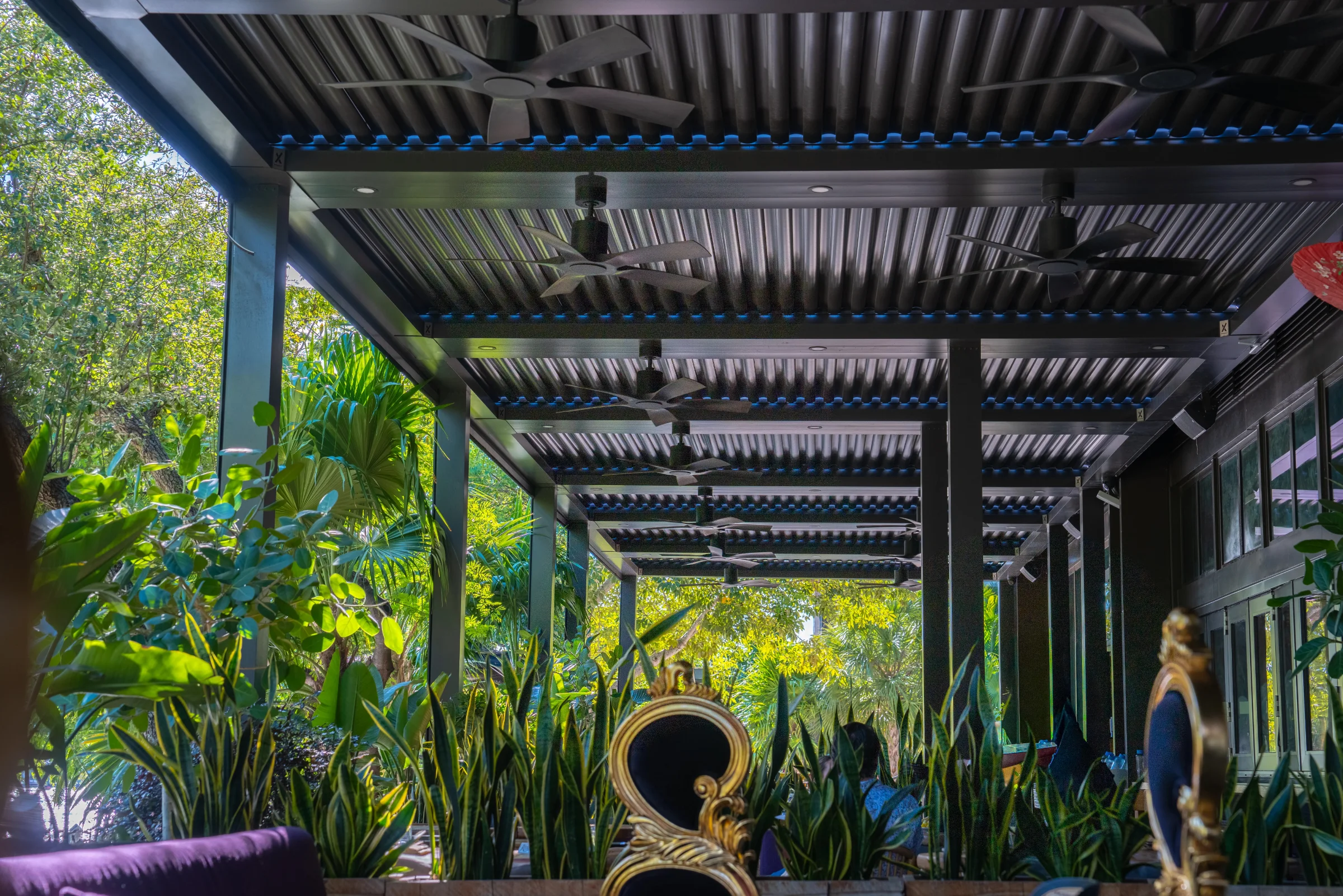 Retail shade structures with louvered roofs over a landscaped mixed-use walkway