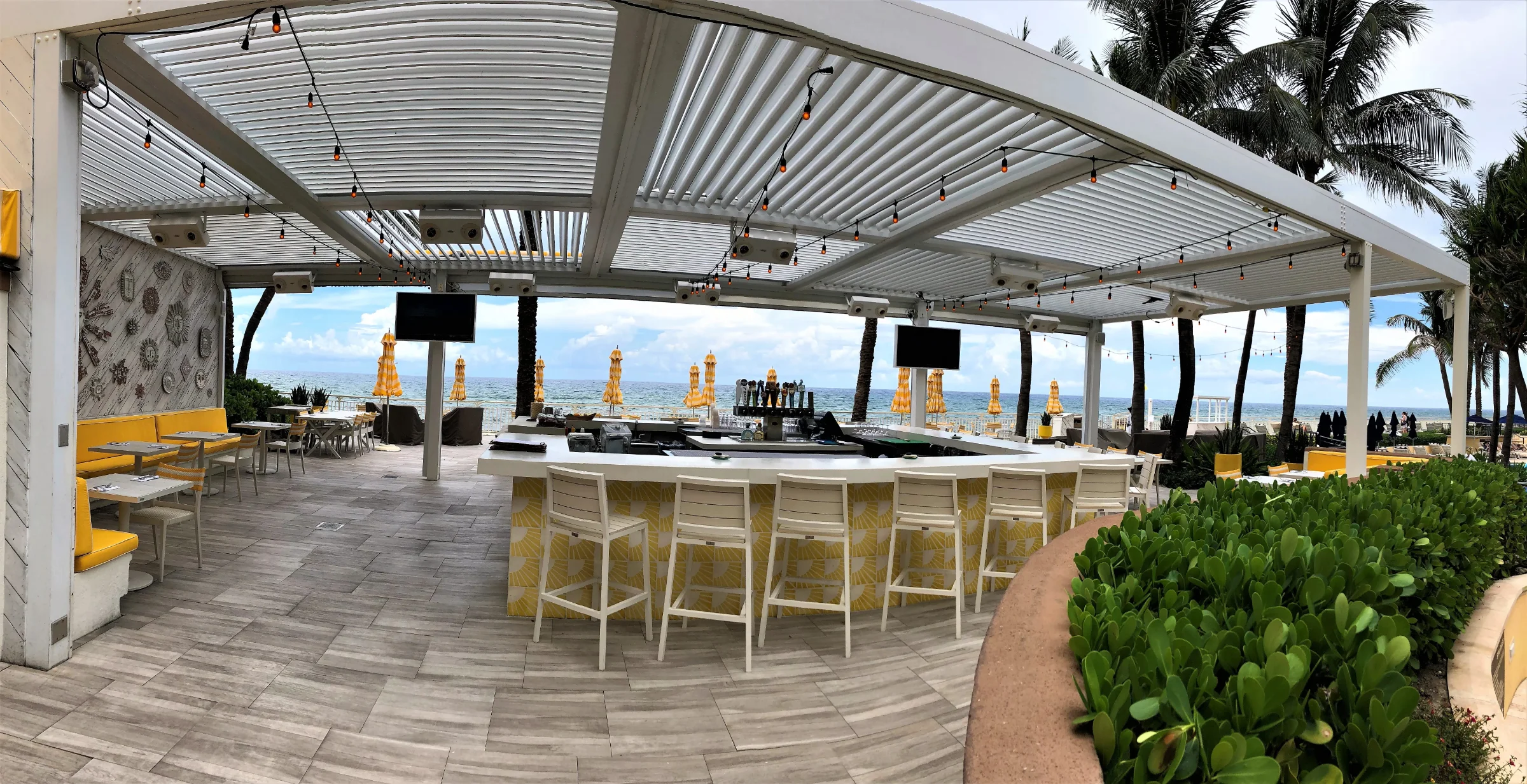 Vacation rental pergola style louvered roof sheltering a poolside bar at a Palm Beach oceanfront property
