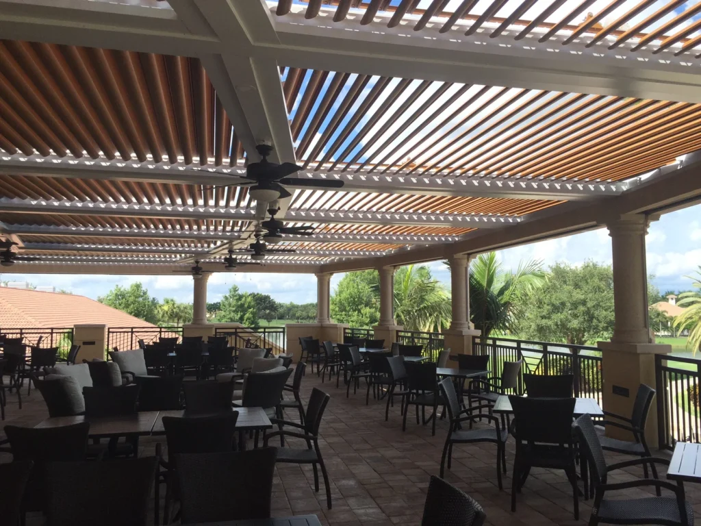 Covered outdoor dining terrace under a louvered pergola roof at a South Florida club