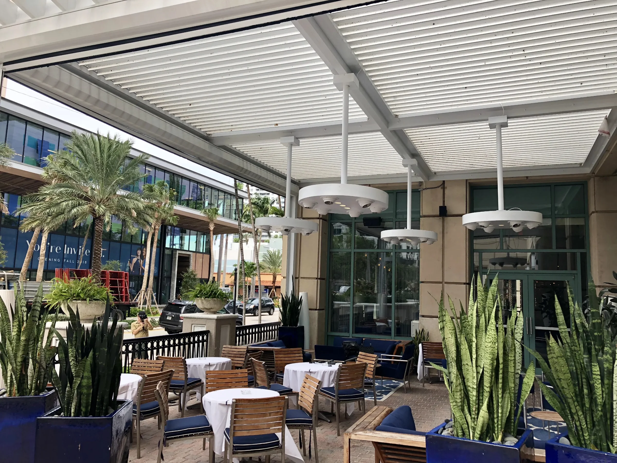 Restaurant patio under an aluminium louvered pergola with screen guide tracks on the columns, Fort Lauderdale