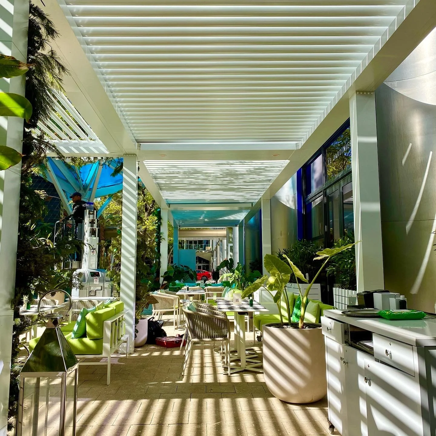 Wall-mounted controls and integrated lighting beneath a motorised louvered pergola in South Florida