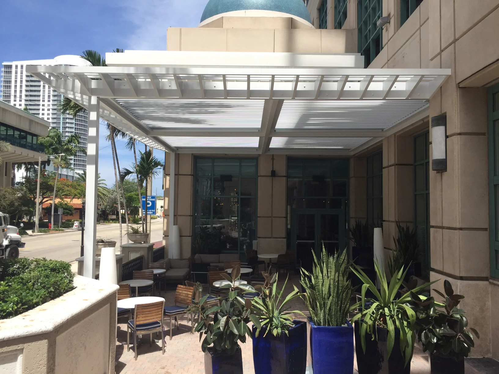 Motorised screen housing mounted at the edge of a louvered pergola roof on a Las Olas Boulevard patio