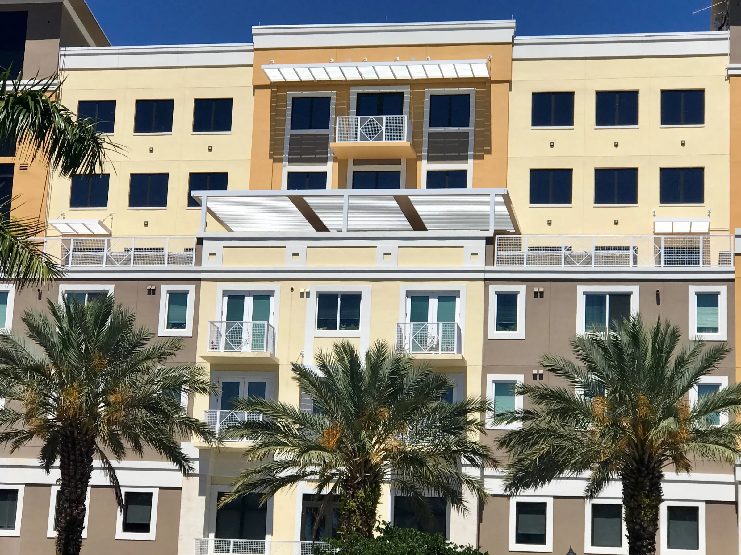 Second-floor terraces with louvered shade structures at a South Florida senior living community