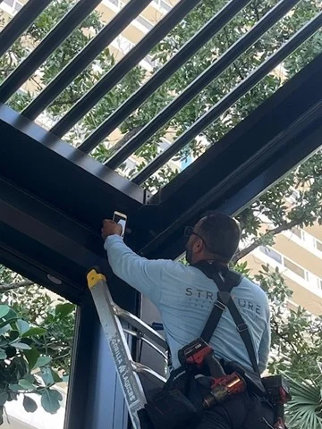 A StruXure technician fitting an aluminium louver on a commercial shade structure in Florida