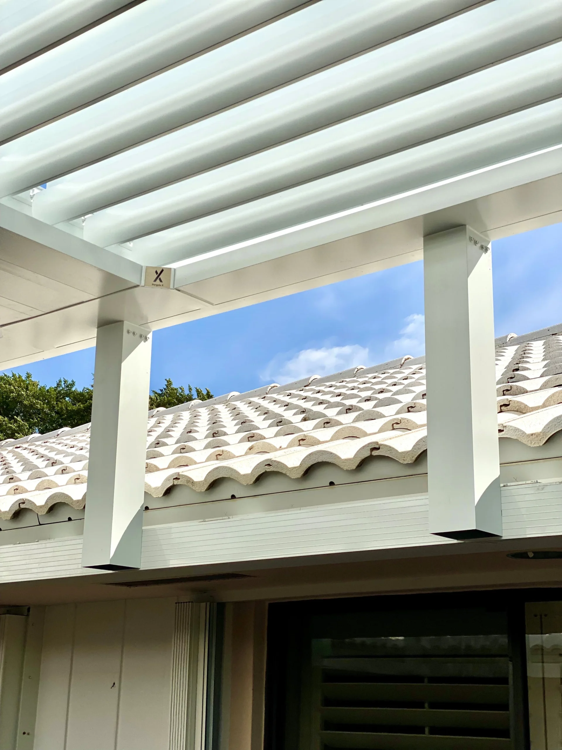 Pergola riser wall framing rising above a barrel tile roof to carry a louvered roof structure