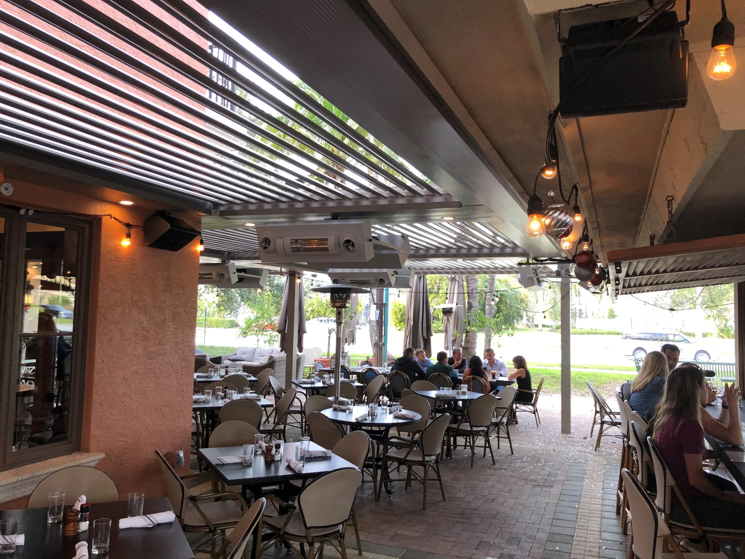 Level paved patio beneath an aluminium louvered pergola in Palm Beach Gardens, with clear paths between tables