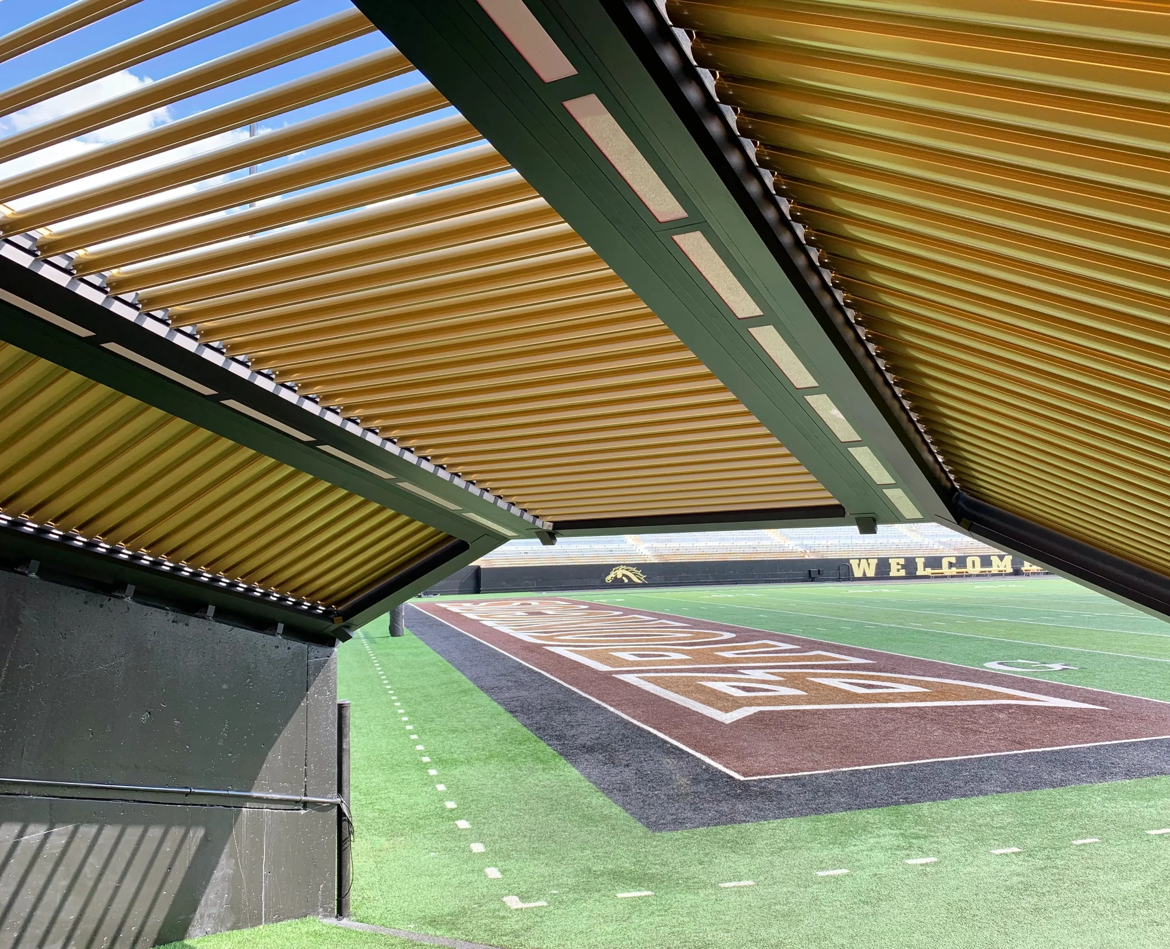 Motorized pergola with wood-grain finish louvers over an outdoor seating area in full sun