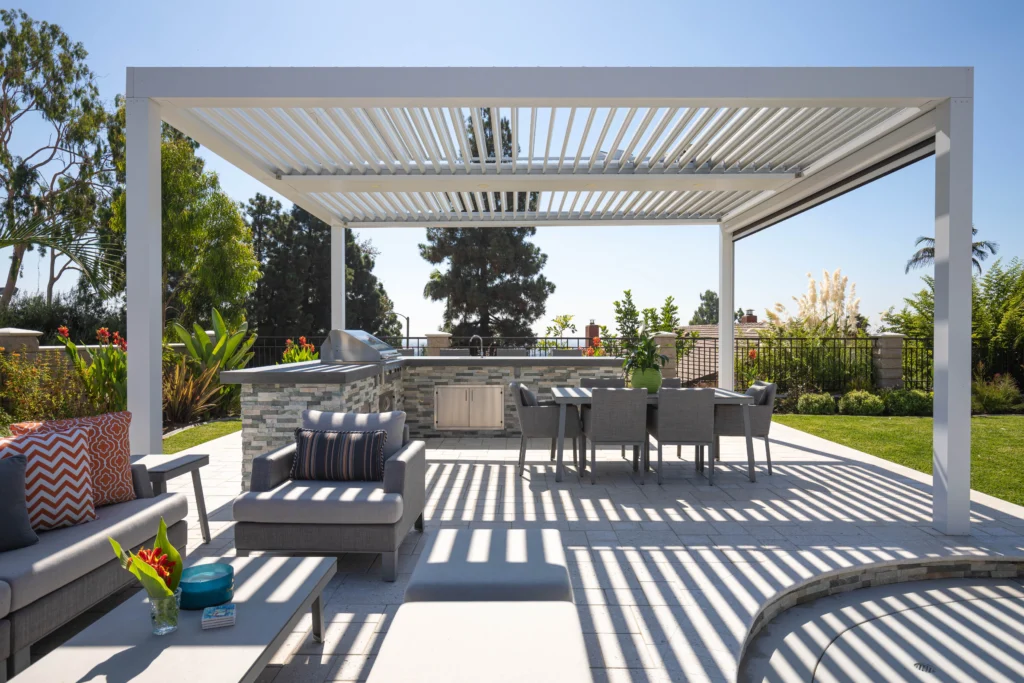 StruXure motorized louvered pergola over a Miami outdoor kitchen and dining area with stone BBQ grill