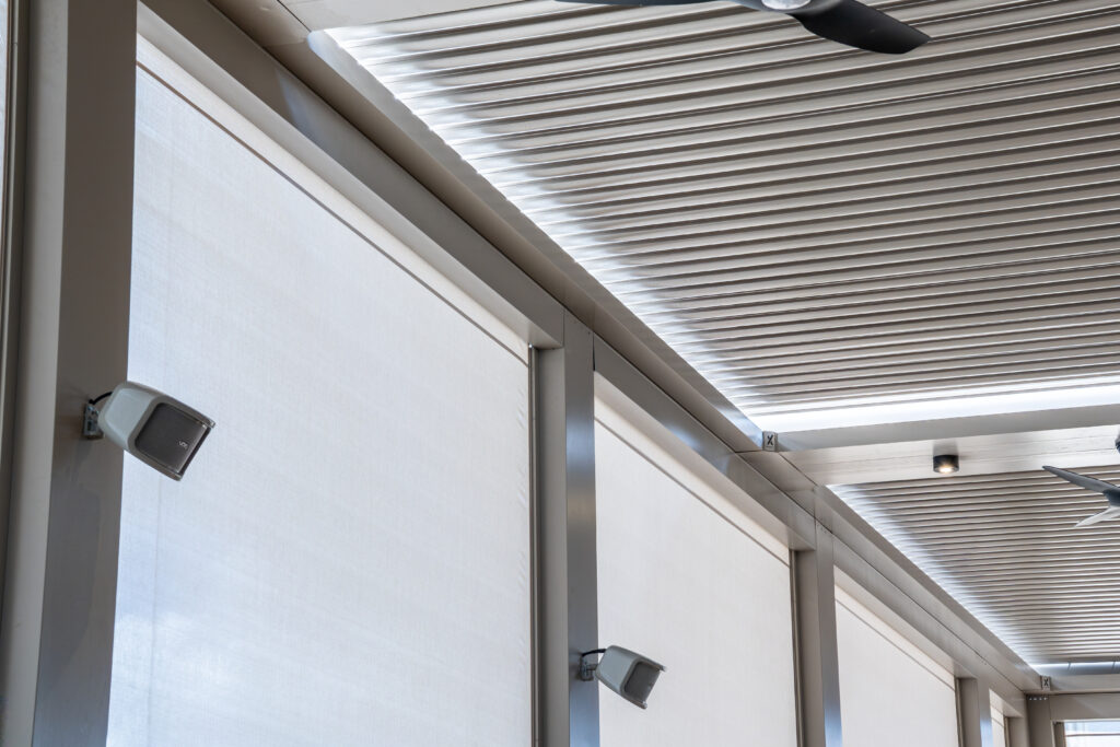 Outdoor living space protected by motorized retractable hurricane screens on an aluminum pergola