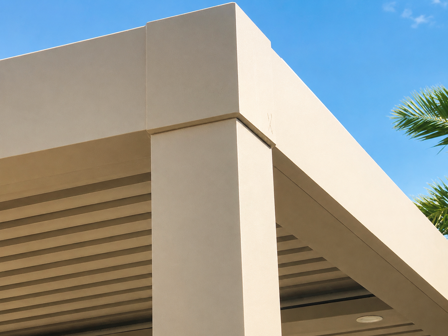 Powder-coated aluminum pergola column detail against a stucco wall