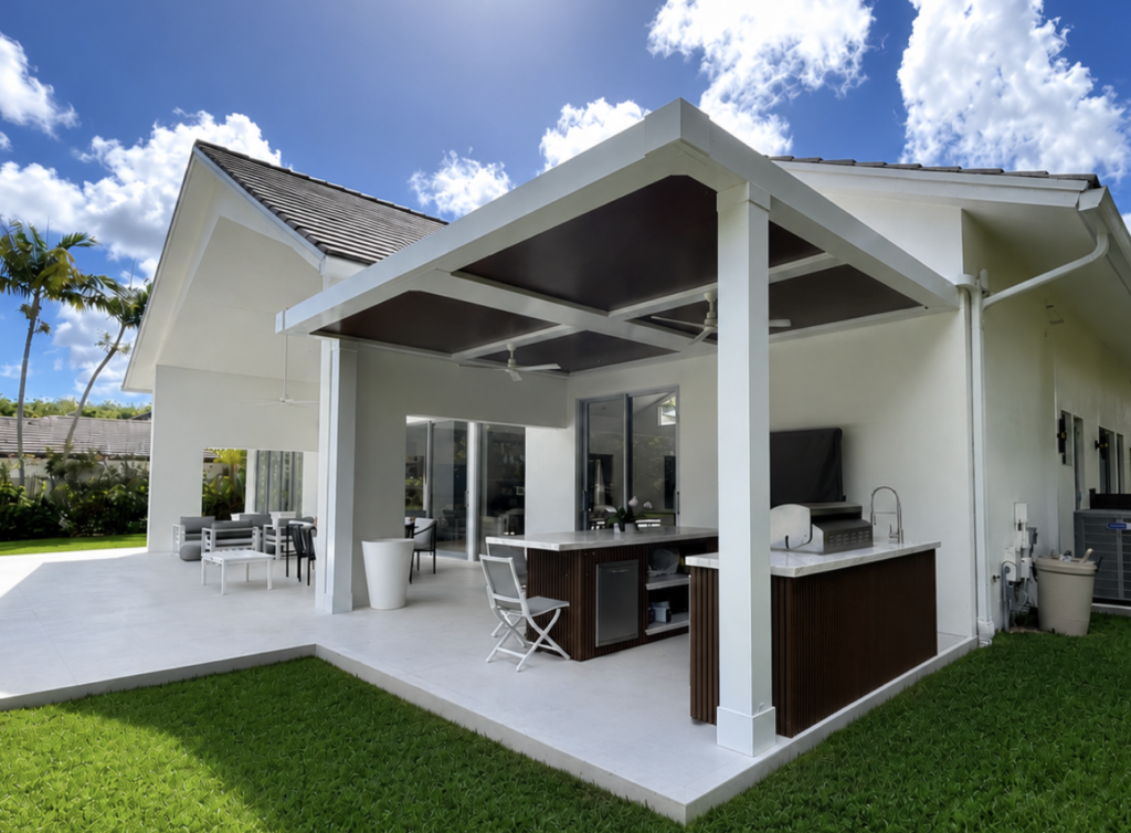 White louvered structure over an outdoor kitchen and dining area in South Florida