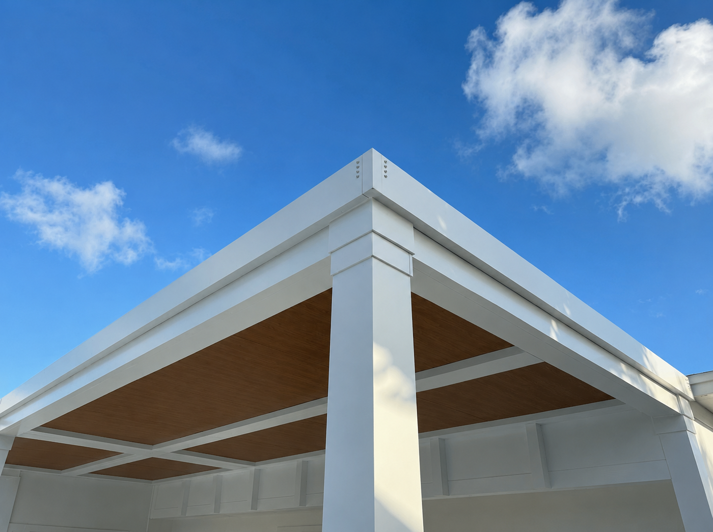 Wood-grain finished aluminium pergola beam against blue sky after a wood pergola replacement
