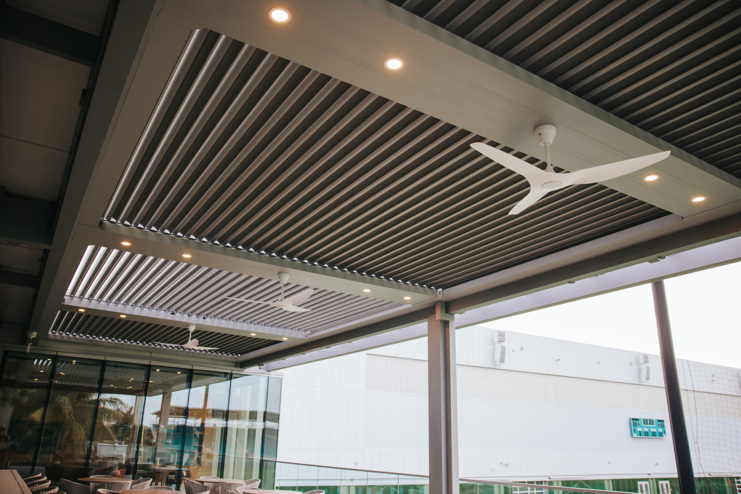 Motorized commercial louvered pergola with ceiling fans over a rooftop hospitality terrace in South Florida